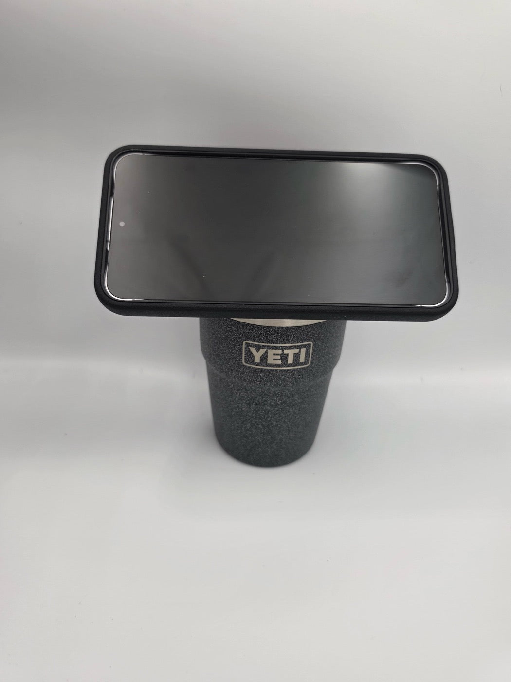 A black YETI tumbler wearing the NMT MagSafe mount with a phone docked on top