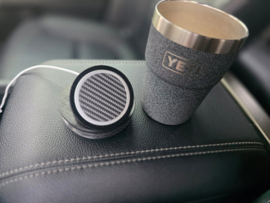 NMT MagSafe mount lid lying face up on a truck armrest beside an open YETI cup