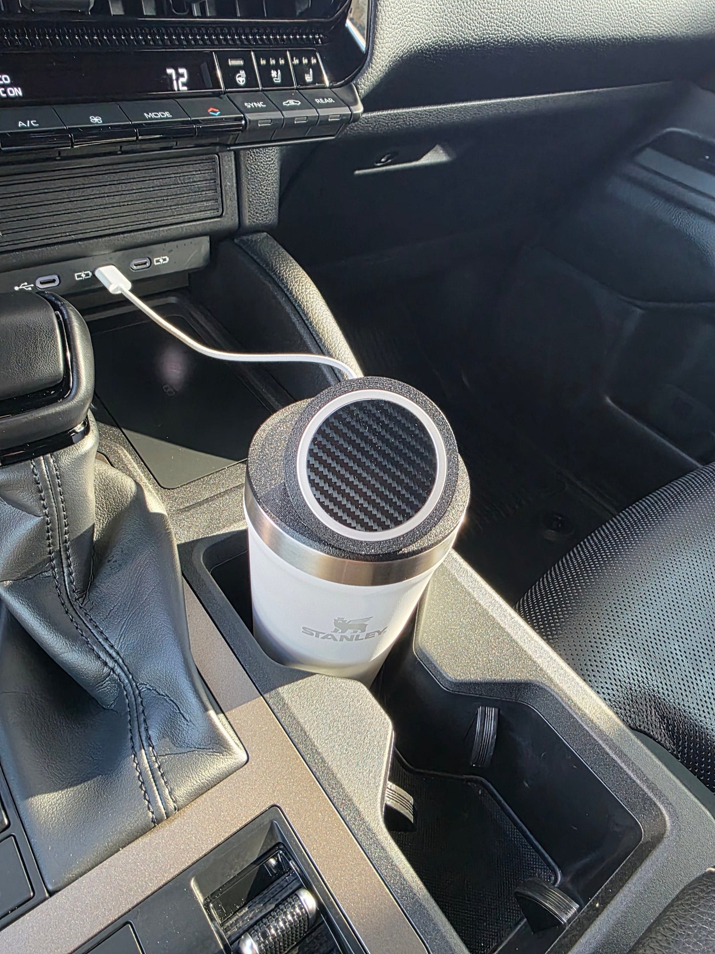 White Stanley 16 oz cup with the MagSafe stand lid in a sunlit truck cupholder, cable running to the dash