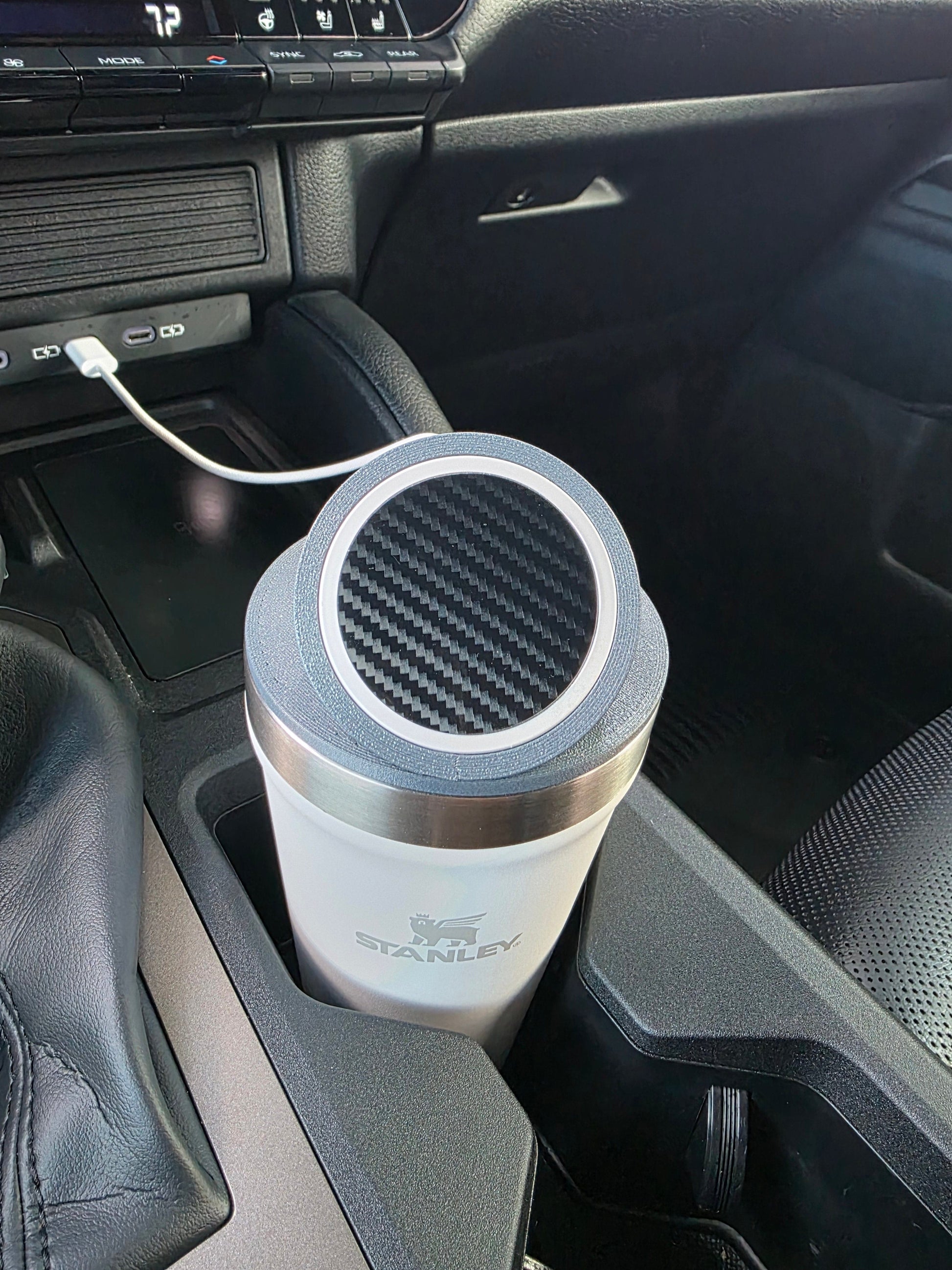 Close-up of the MagSafe stand lid's magnetic pad on a white Stanley 16 oz cup in a truck console