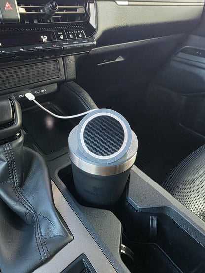Dark tumbler wearing the MagSafe stand lid in a truck cupholder, cable routed from the dash port
