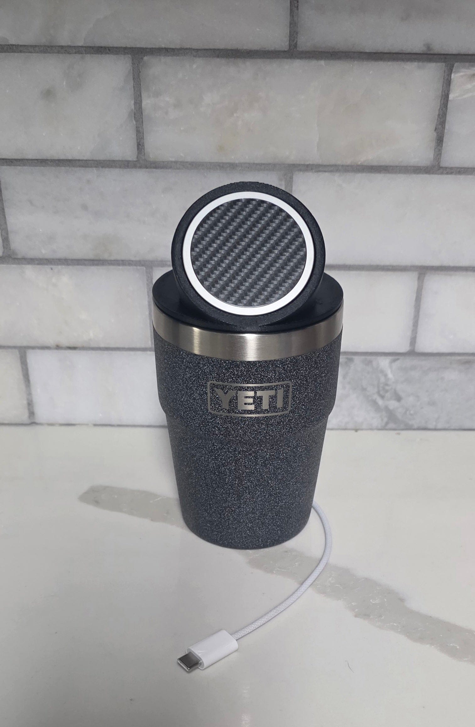 YETI cup with the black MagSafe stand lid tilted up on a kitchen counter, USB-C cable alongside