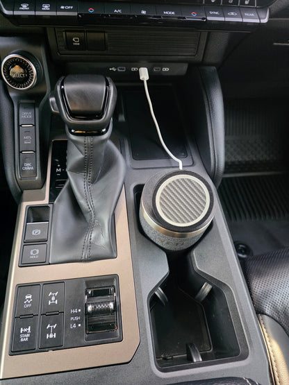 YETI cup wearing the MagSafe stand lid in a truck cupholder, charging cable routed from the dash