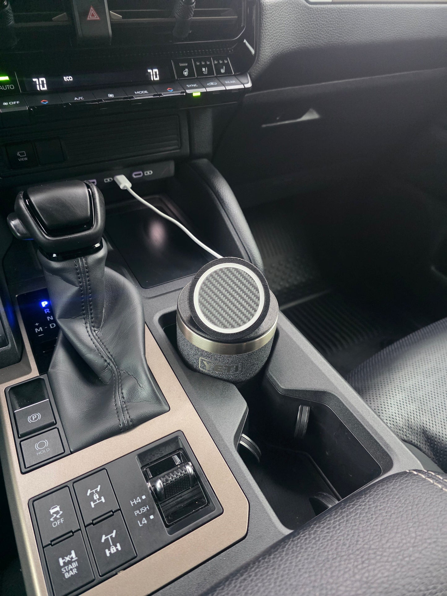 Black MagSafe stand lid tilted up on a YETI cup in a truck console cupholder