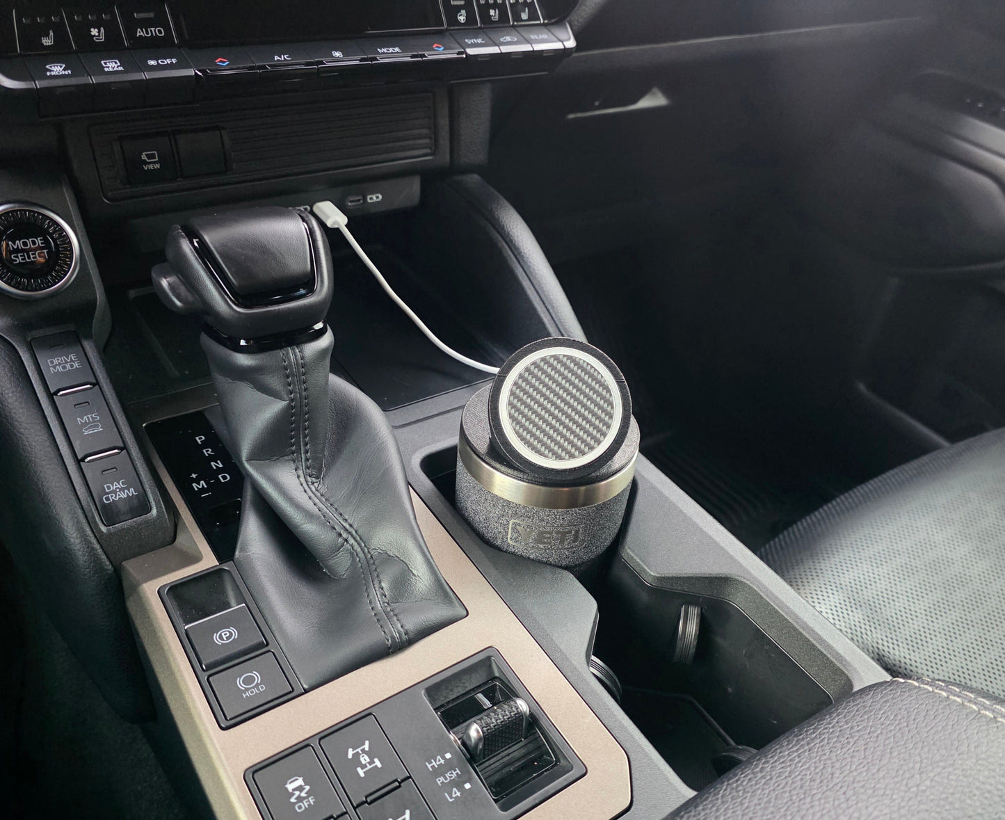YETI cup with the MagSafe stand lid in a truck console cupholder, charging cable running to the dash