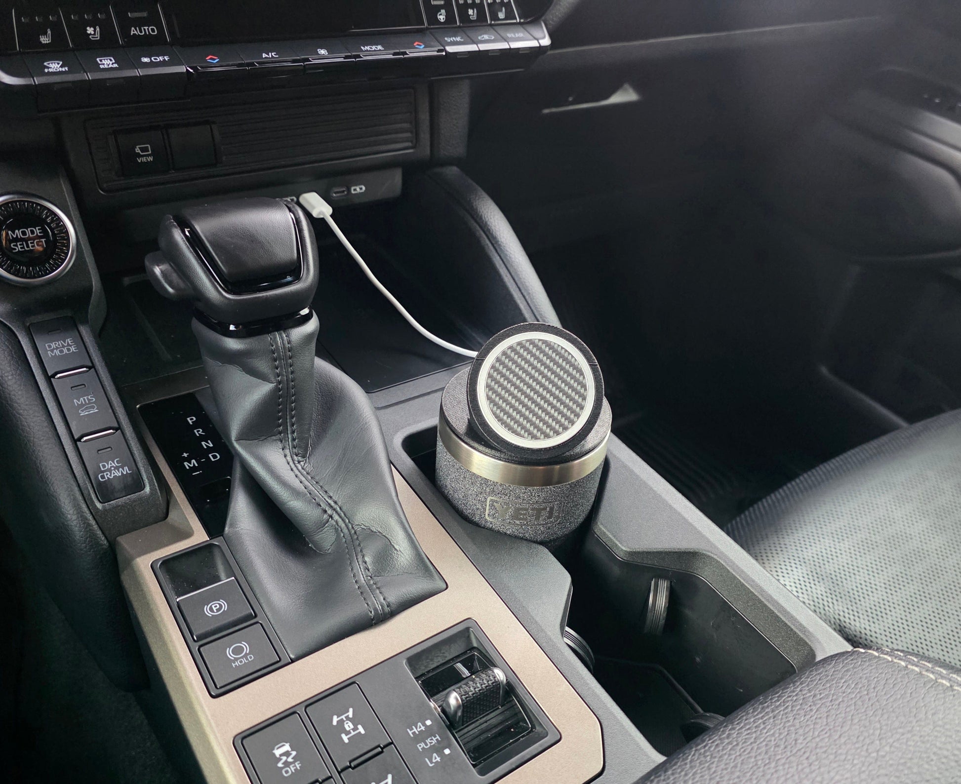 YETI cup with the MagSafe stand lid in a truck console cupholder, charging cable running to the dash