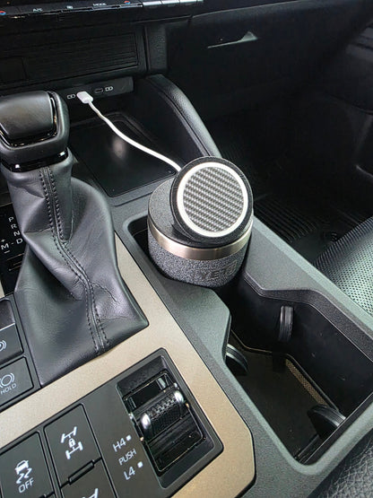 Black YETI cup in a truck console cupholder with the MagSafe stand lid tilted up, charging cable running from the dash