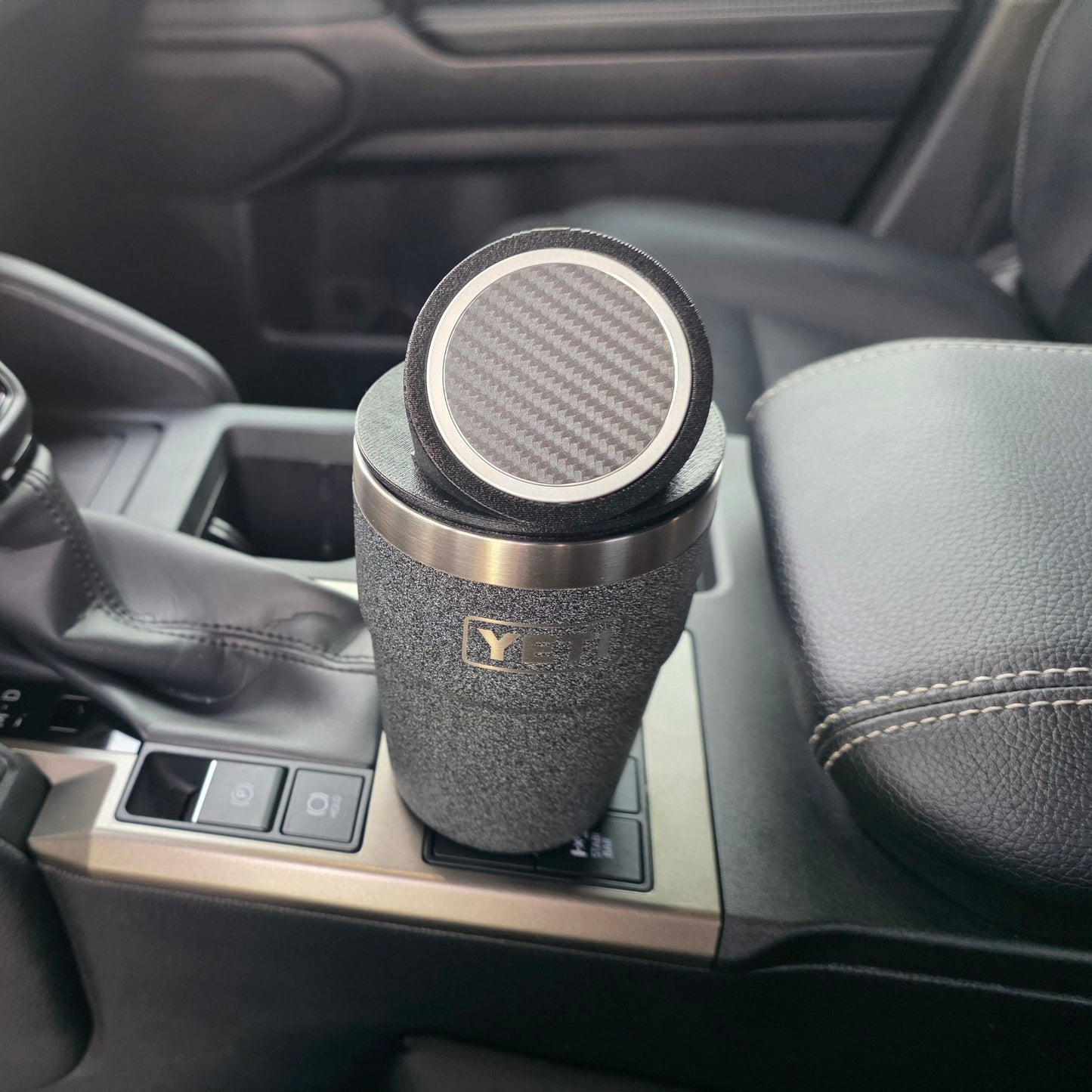 Close-up of a black YETI cup with the MagSafe stand lid tilted, sitting in a truck console