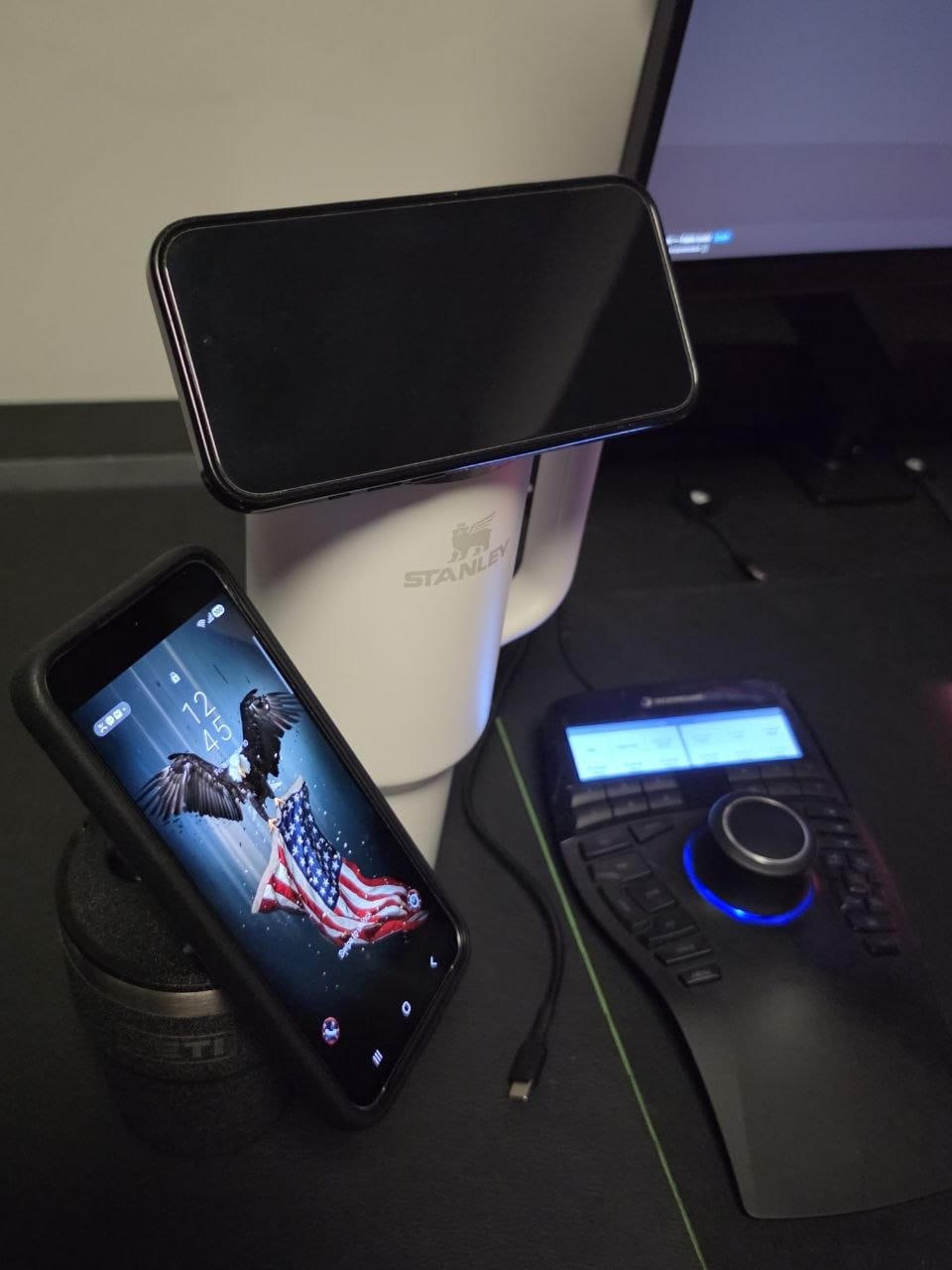 Two phones on MagSafe stands on a desk with the charging cable routed to the cups