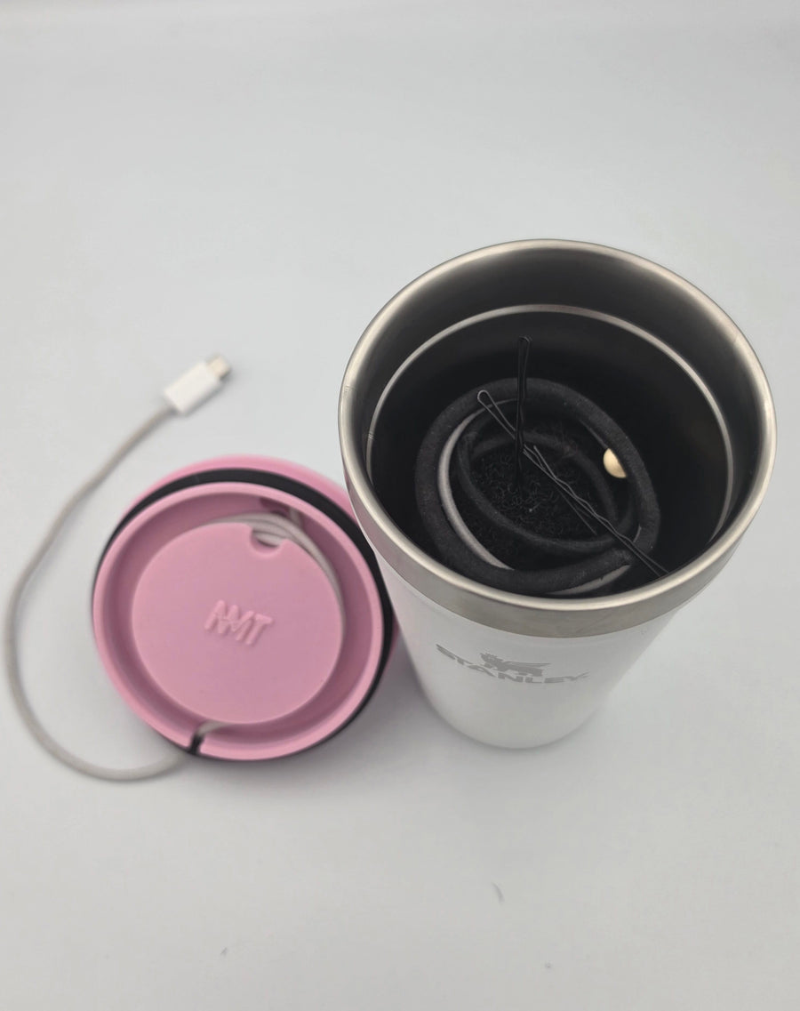 A pink NMT mount set aside next to a Stanley tumbler holding hair ties and bobby pins