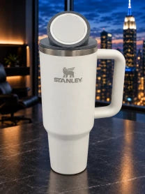 Gray NMT replacement lid fitted to a white Stanley cup beside a city window.