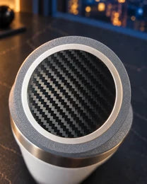 Close-up of a black carbon-pattern Charger Skin on a charging puck inside a gray NMT ring.