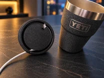 Underside of the NMT lid showing cable routing beside an empty YETI cup.